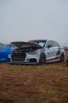 Image of a sleek Audi Sport sedan with an open hood on a grassy field.