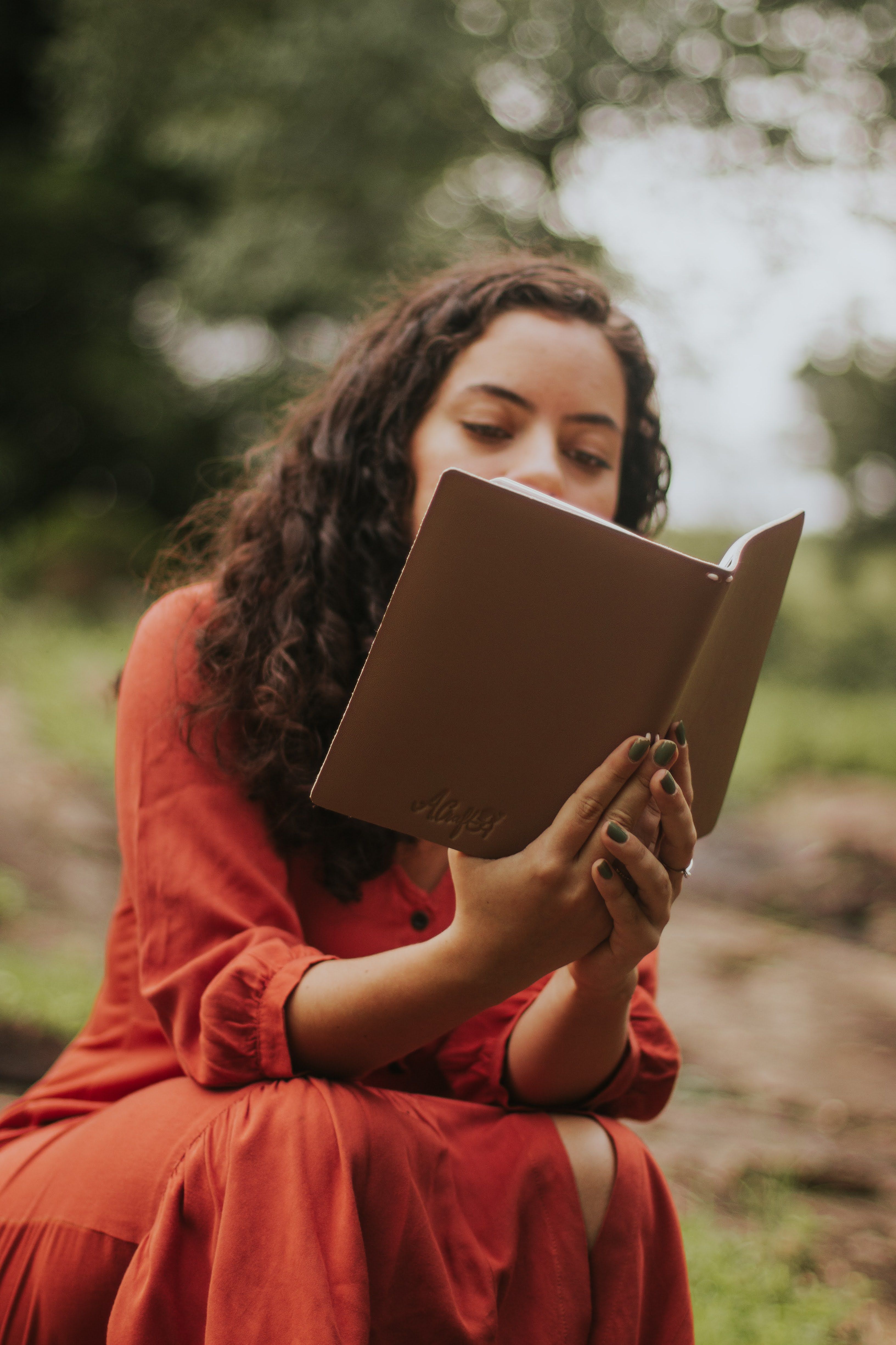 Young woman in red dress reading outdoors. Peaceful and serene setting in nature.