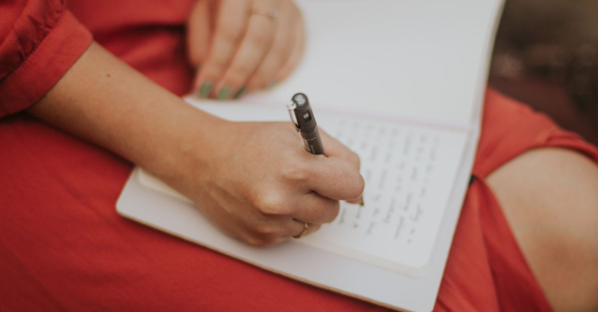 person writing in a paper journal with a pen, simple setting