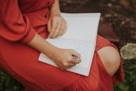 Woman Writing in Journal Outdoors in Red Dress