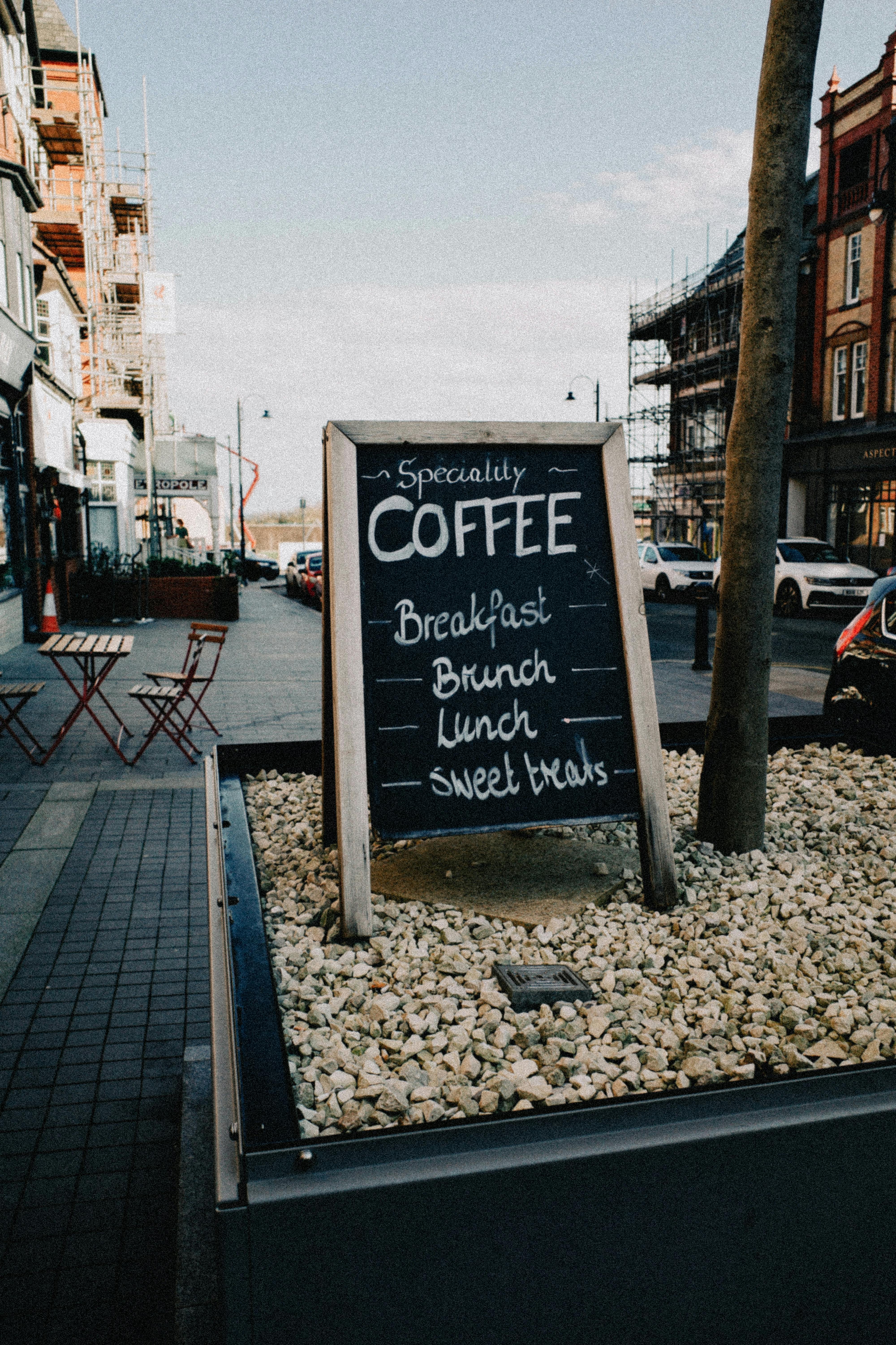 Chalkboard menu promoting coffee and meals on a lively street in Colwyn Bay, Wales.