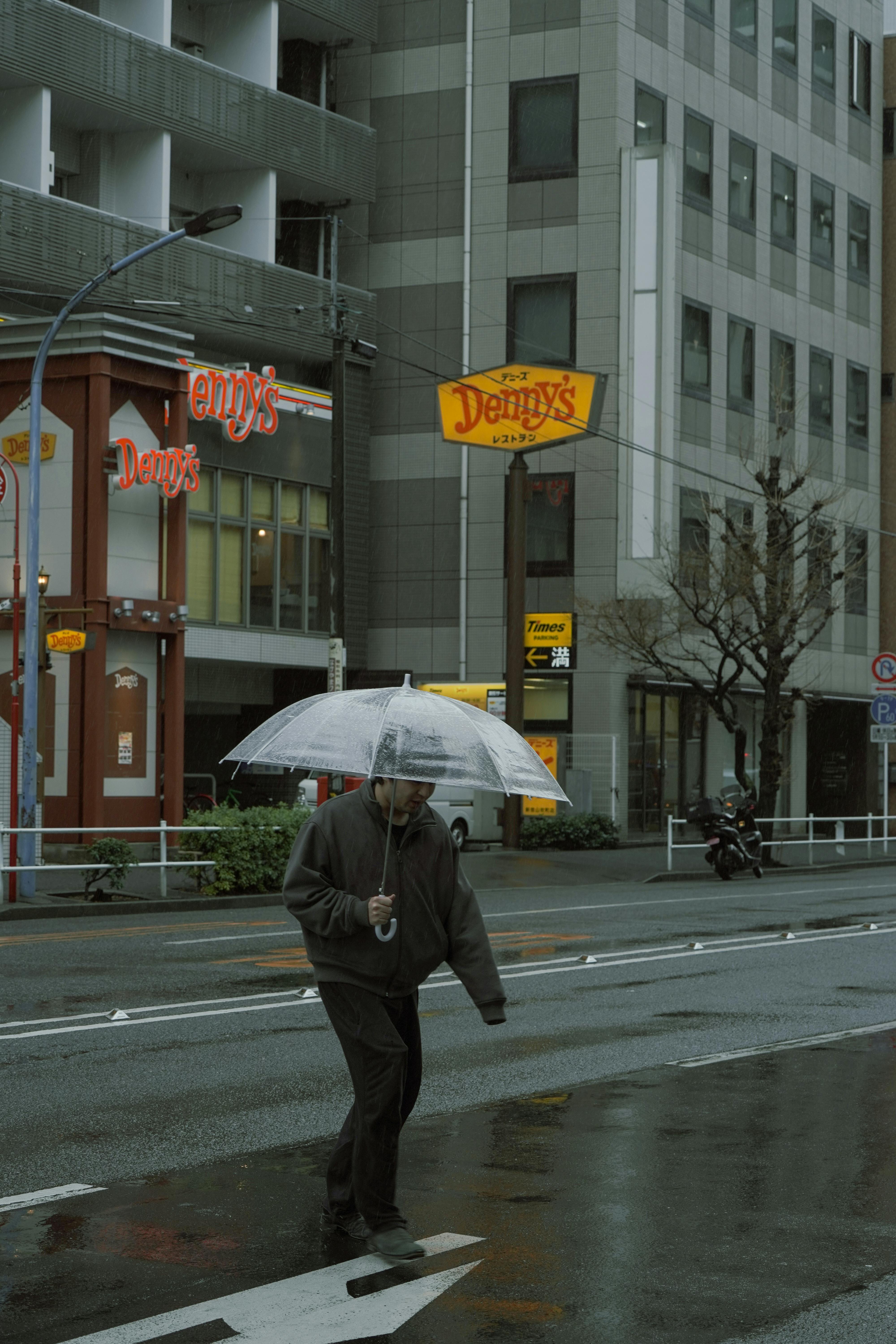A person walks with an umbrella by a Denny's in rainy Tokyo, Japan.