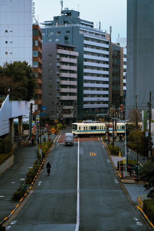 Free Street scene capturing a tram and cyclist in Tokyo amid tall buildings. Stock Photo