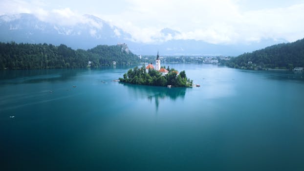 Stunning aerial view of Lake Bled with the Church of the Assumption on the island, surrounded by mountains.