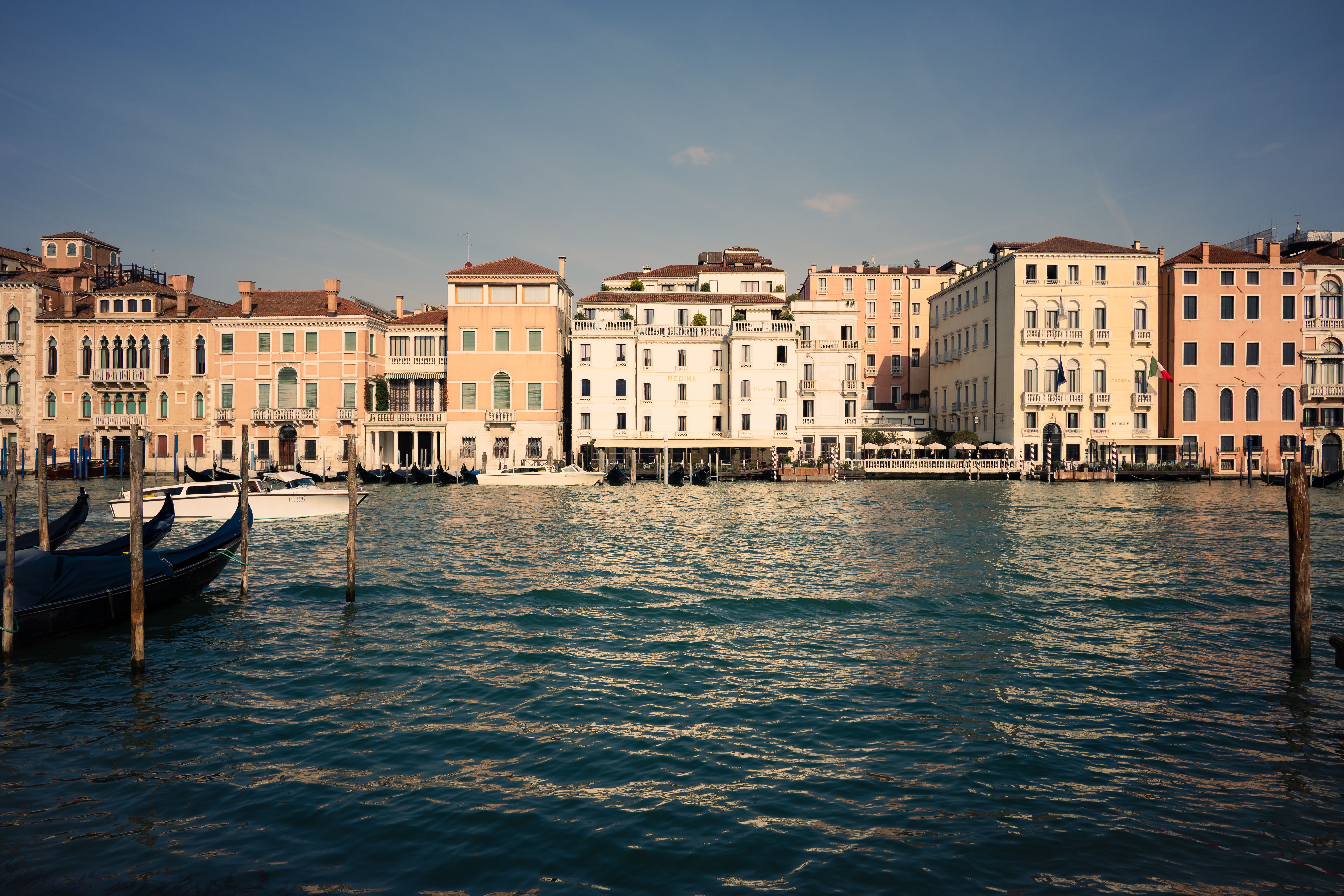 Charming view of Venice's historic architecture along a serene canal, under a clear blue sky.