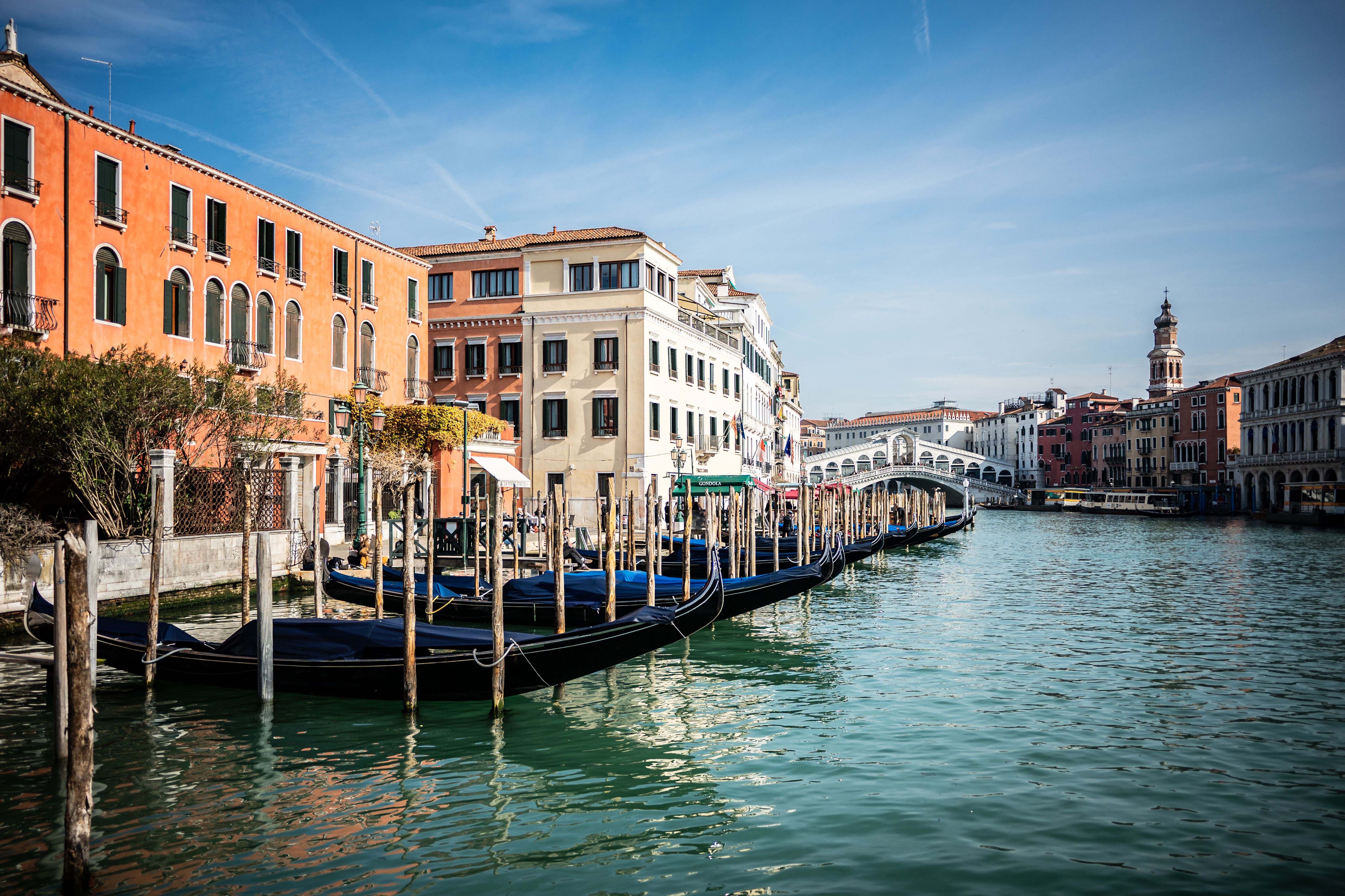 Beautiful Venetian canal view with gondolas and Rialto Bridge on a sunny day.