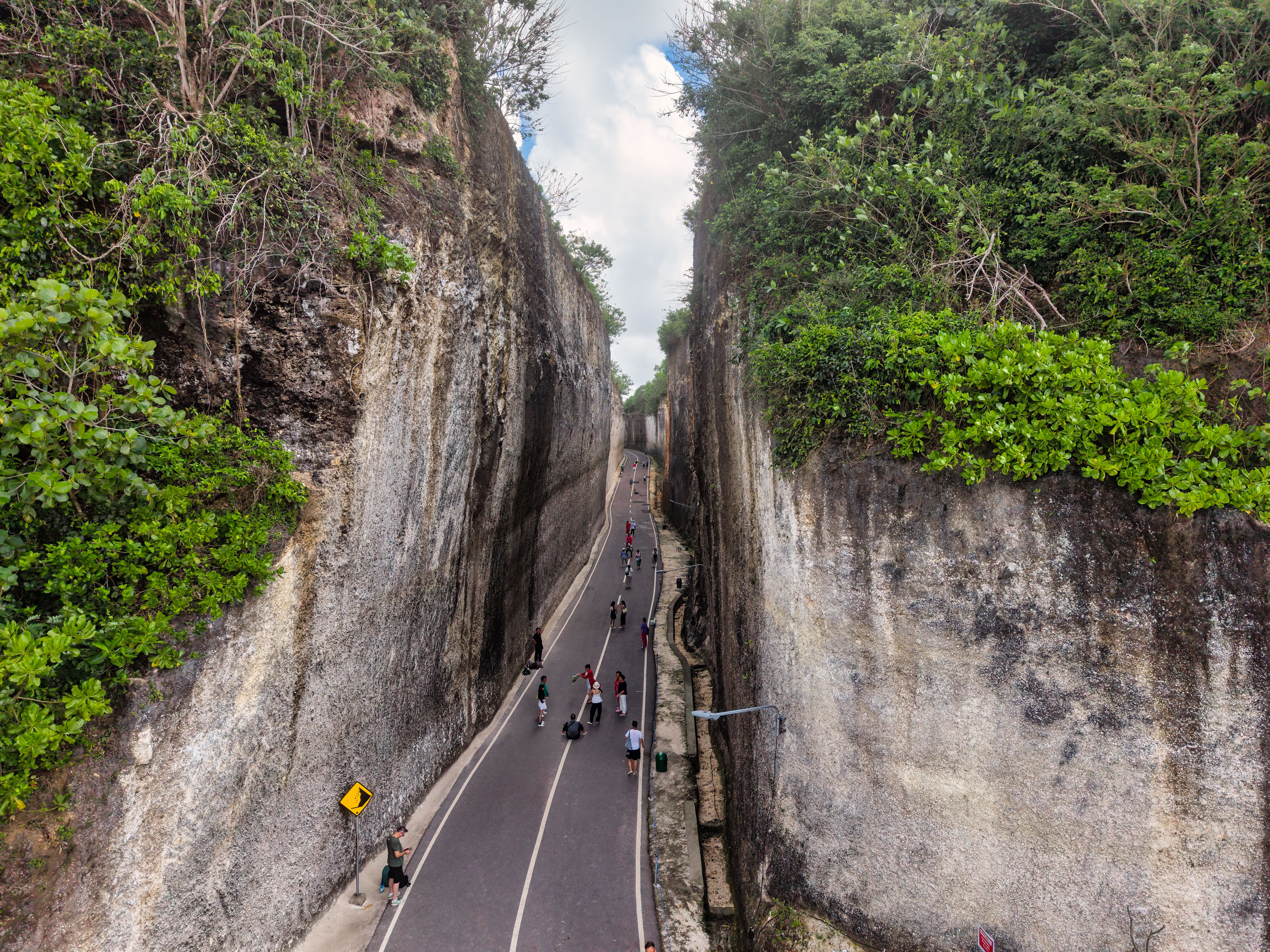 Breathtaking aerial view of a gorge pathway in Bali, featuring people walking and lush greenery.