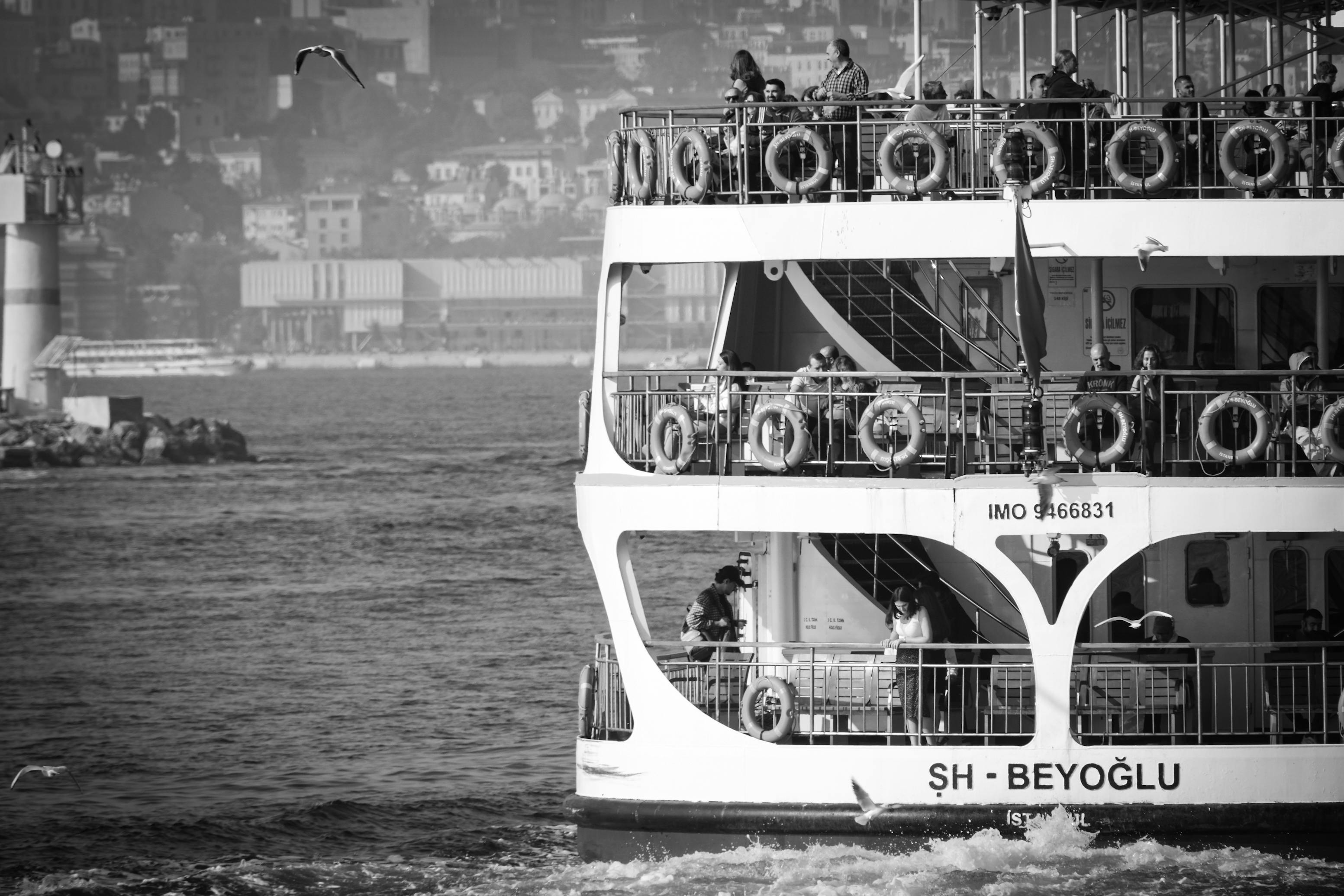 Black and white photo of ferry on Bosphorus with Istanbul cityscape in the background.