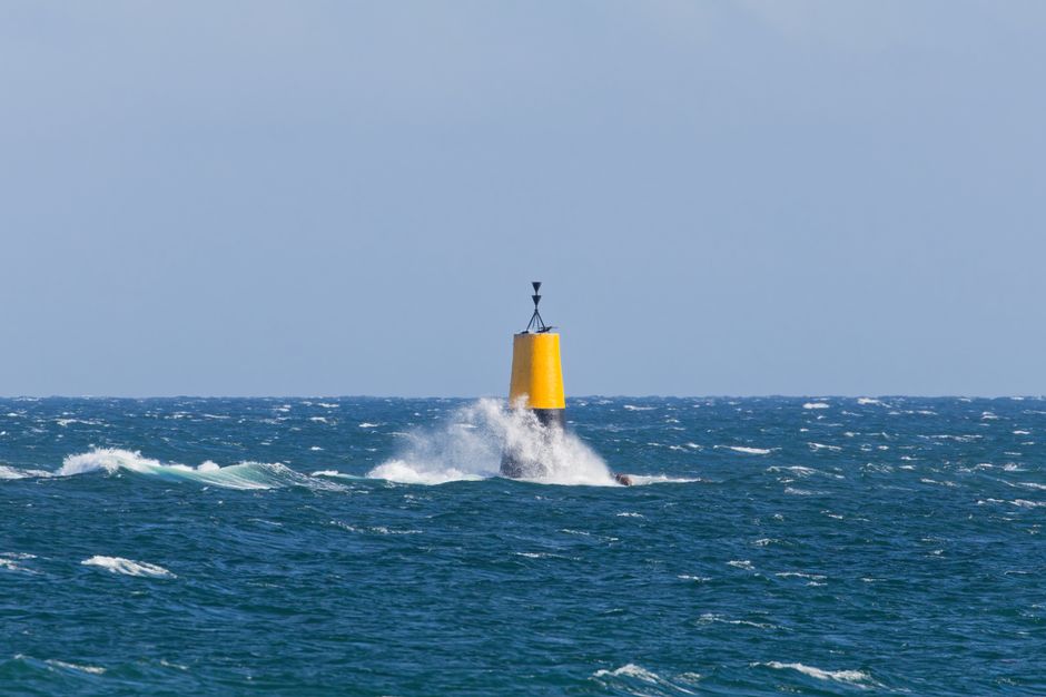 A bright yellow buoy amidst crashing waves in the Atlantic Ocean off the coast of Brittany, France.
