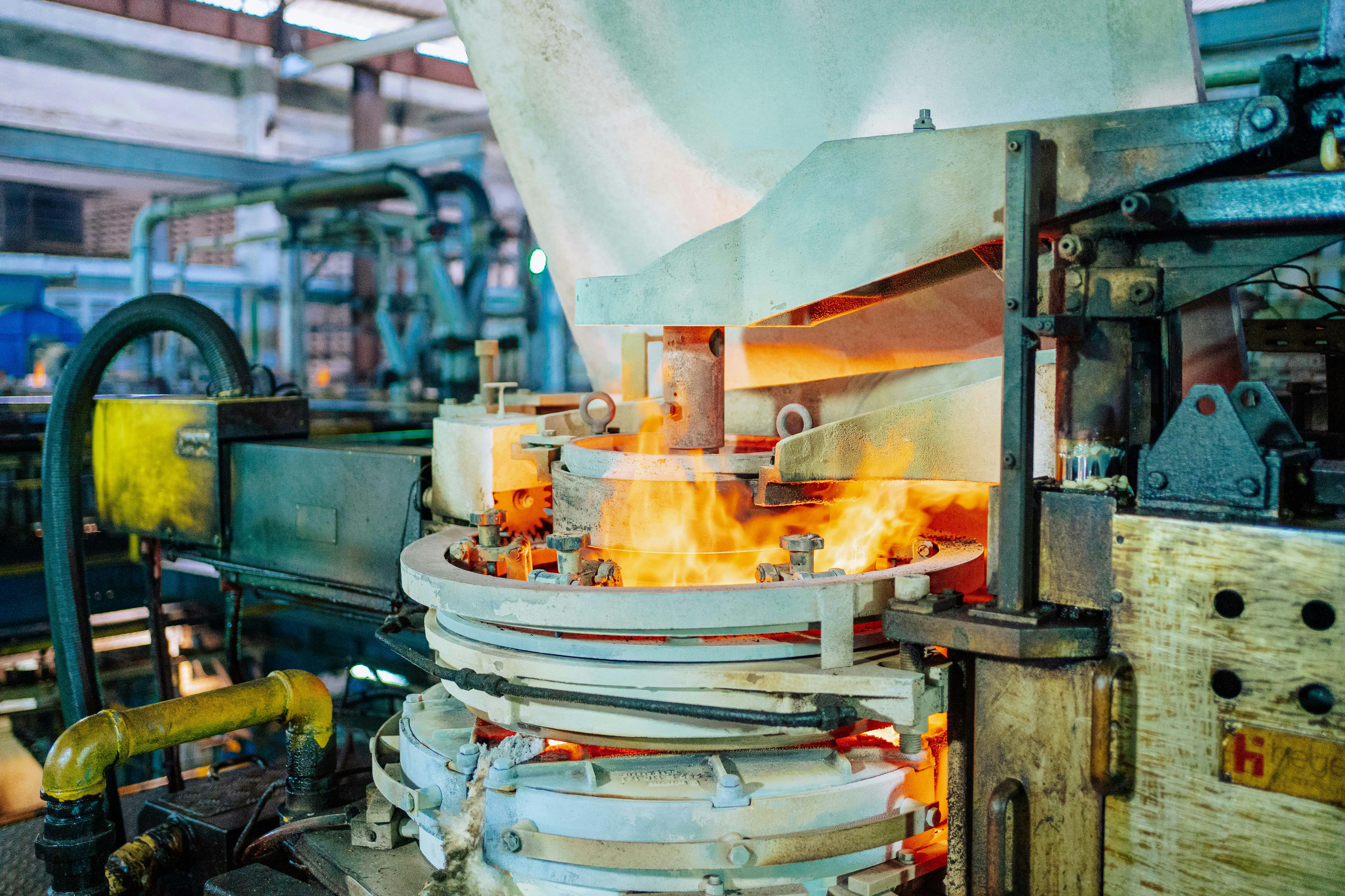 Fiery glassmaking process in a Dar es Salaam factory showcasing industrial machinery.