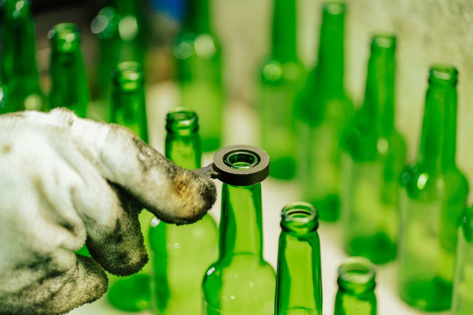 Close-up of a worker handling green glass bottles in a factory setting in Tanzania.