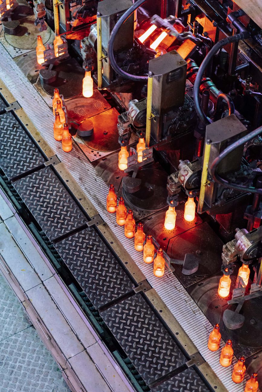 High-angle view of glass bottle production line in a factory with glowing bottles.