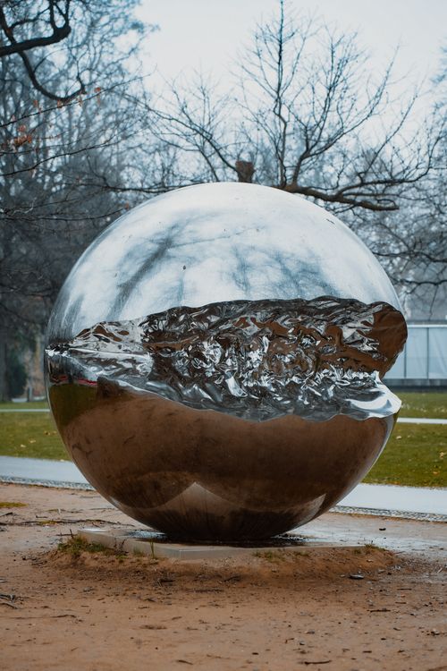 Free Captivating metallic sphere sculpture amidst a serene Lugano park setting. Stock Photo