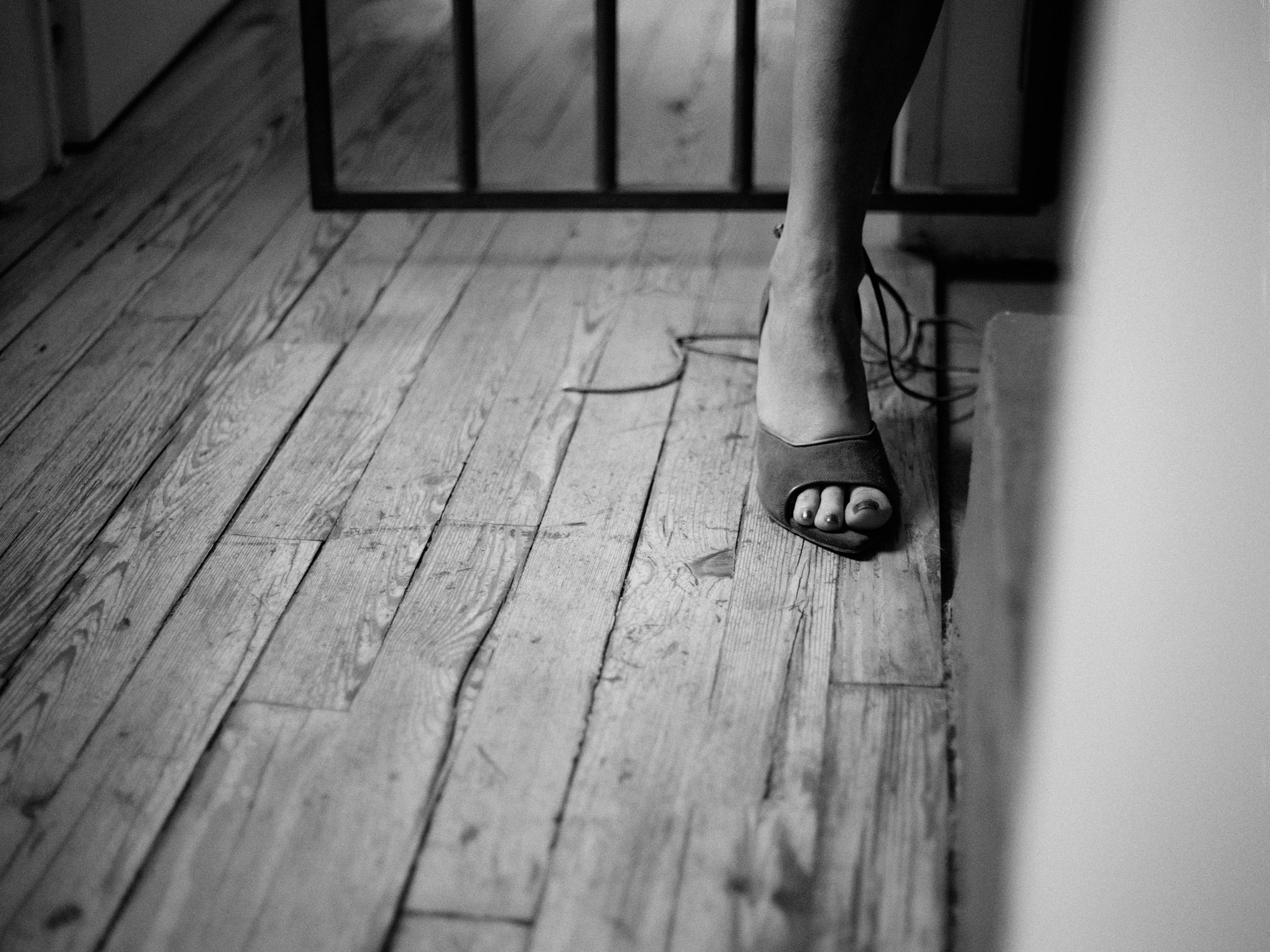 De franc Foto minimalista en blanc i negre del peu d'una dona amb un taló alt sobre un terra de fusta, que transmet elegància. Foto d'estoc