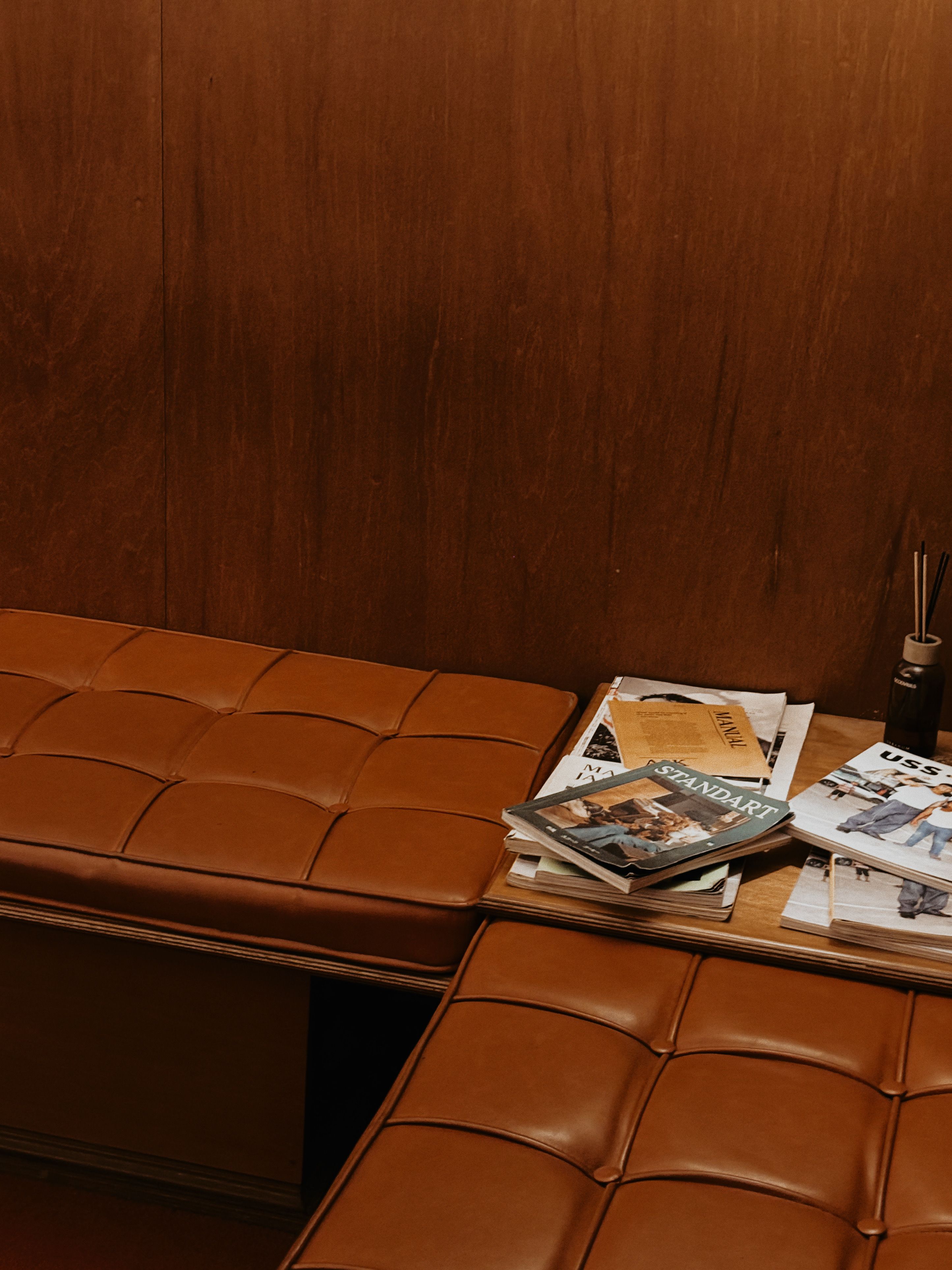Warm cozy seating area with brown leather seats and magazines for a relaxed atmosphere.