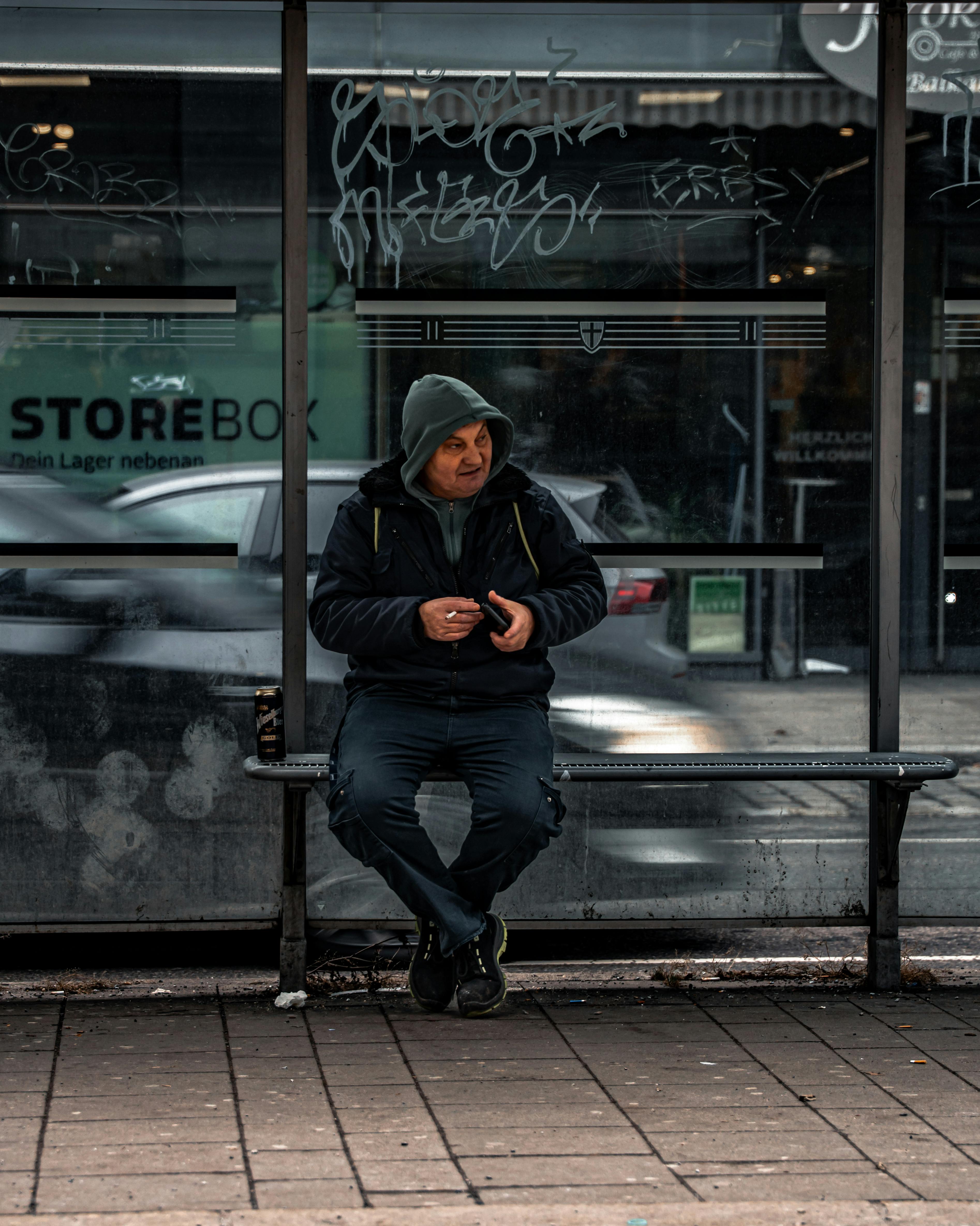 Free An adult man in warm clothing waits at a bus stop in Vienna. Urban winter setting. Stock Photo