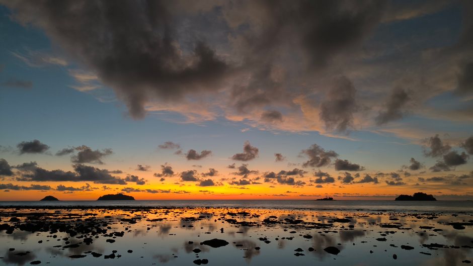 Breathtaking sunset over Koh Samui, Thailand, with dramatic clouds and calm sea reflections.