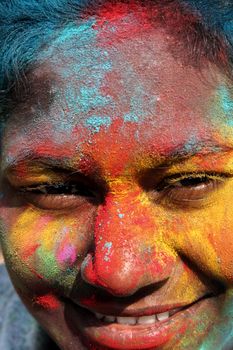 Close-up of a joyful face covered in colorful Holi powders during the vibrant festival in India.