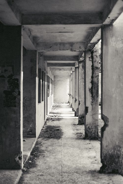 Free A monochrome photo of an abandoned corridor in Jos, Nigeria, showing decay and shadows. Stock Photo