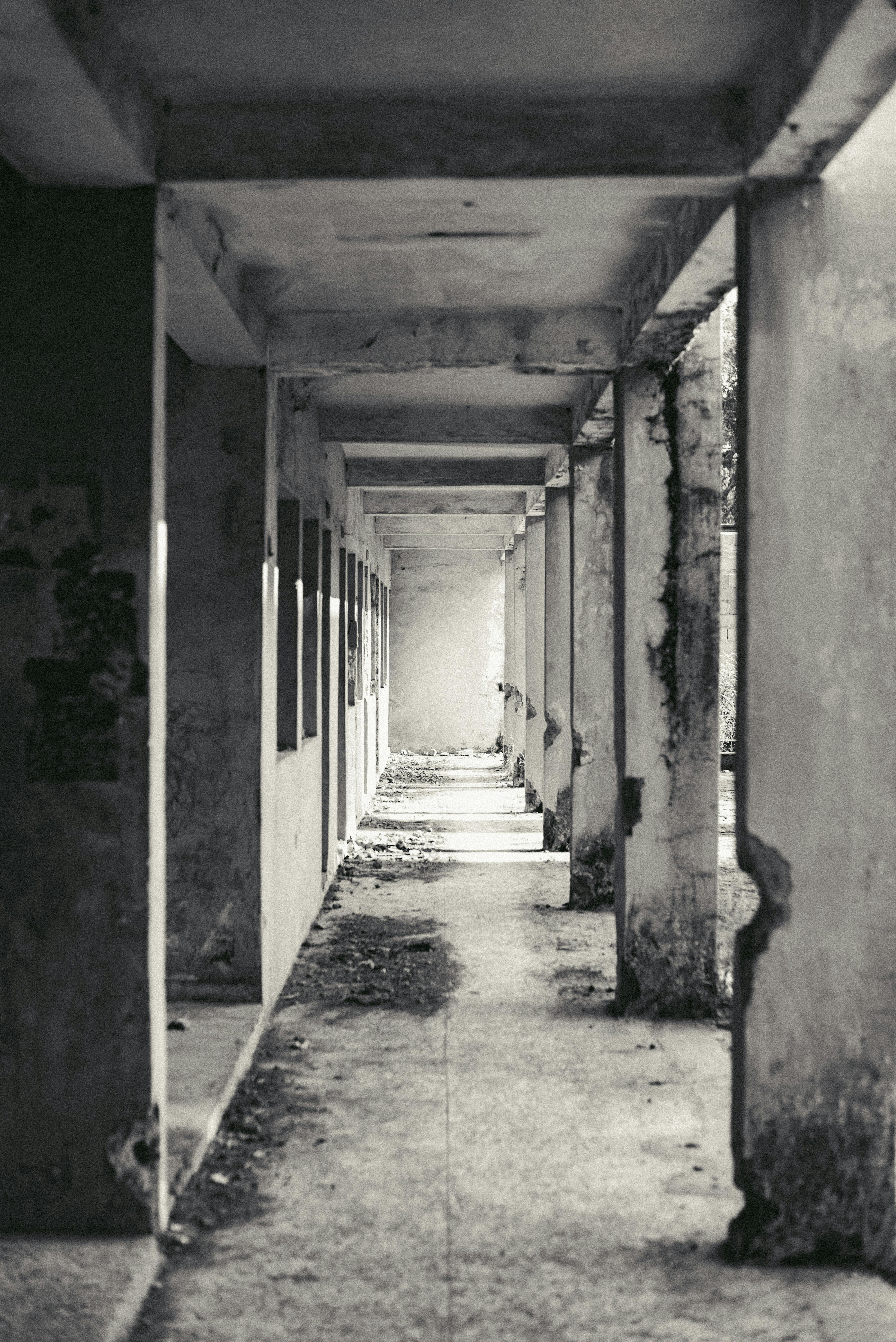 Bezpłatne Monochromatyczne zdjęcie opuszczonego korytarza w Jos w Nigerii, ukazujące rozkład i cienie. Zdjęcie z galerii