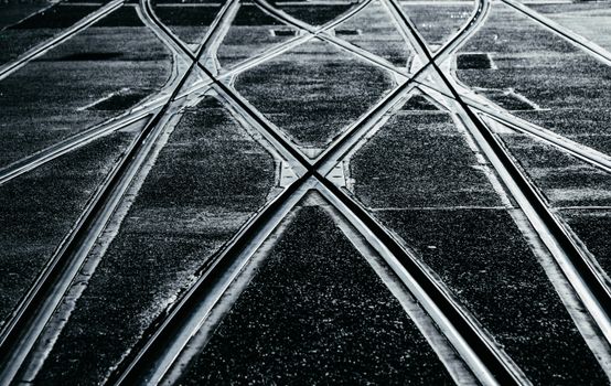 Black and white photo of intersecting train tracks captured in a dramatic light.