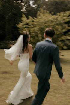 Elegant bride and groom walking together outdoors in a lush garden setting.