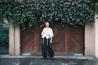Stylish Woman Standing by Flower-Covered Doorway