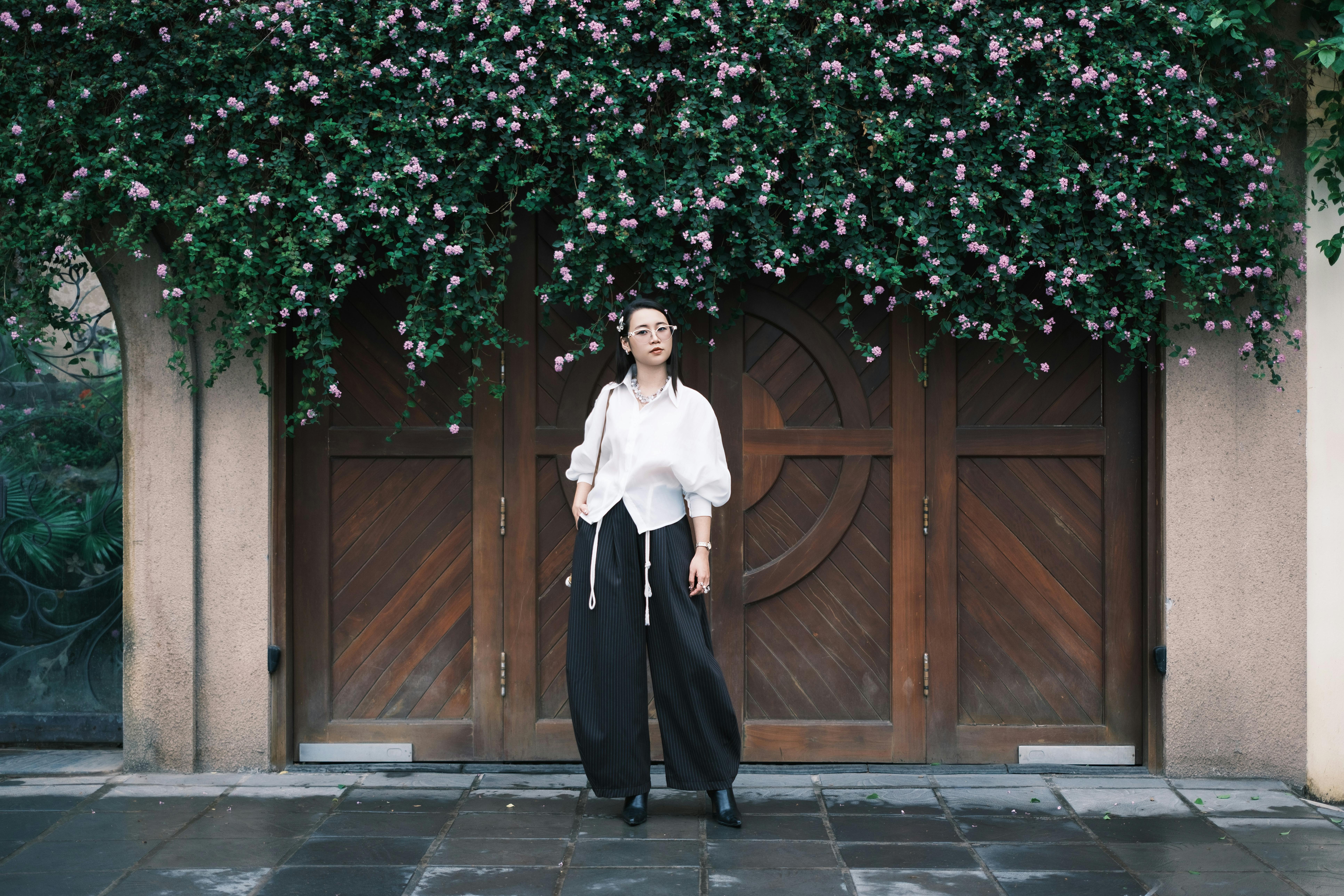 Stylish Woman Standing by Flower-Covered Doorway