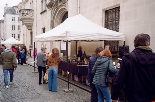 Free Outdoor street market in Nancy, France with people browsing stalls on a cobblestone street. Stock Photo