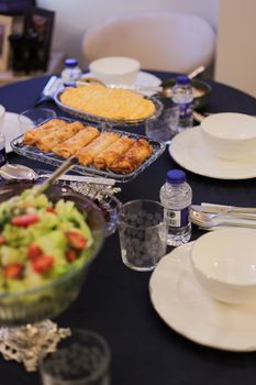 An elegant dining setup featuring Turkish cuisine with salad, water bottles, and cozy indoor setting.