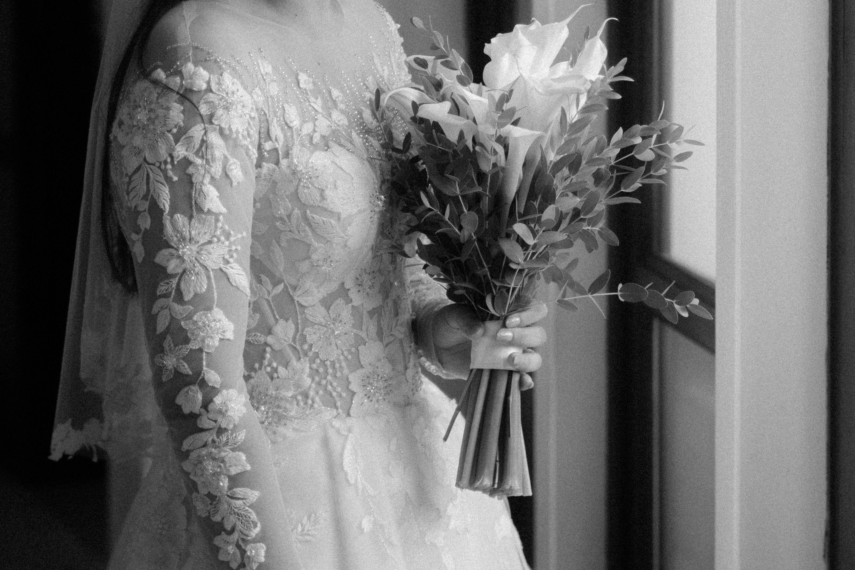 A bride in a lace gown holds a bouquet, embracing elegance and romance.