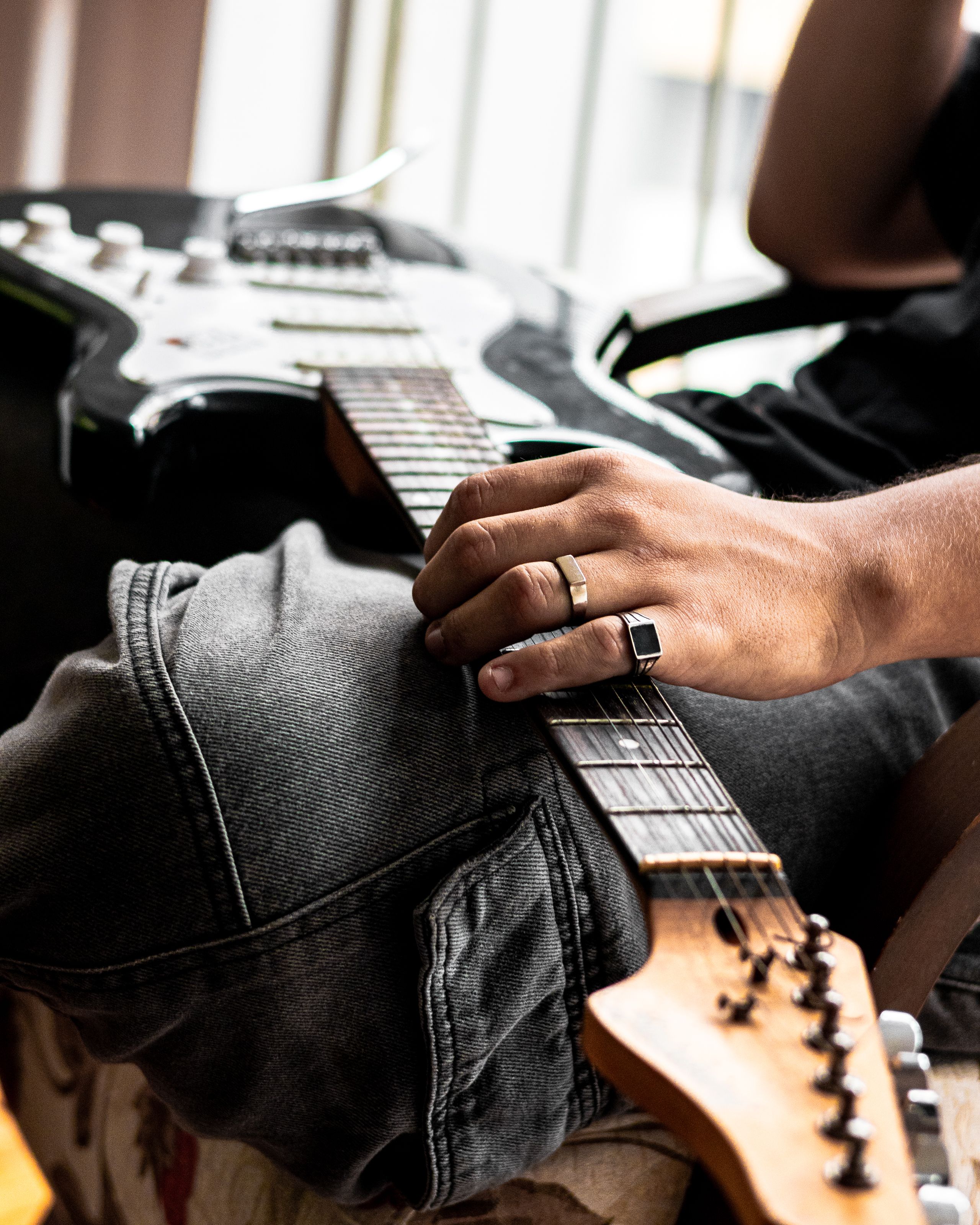Close-up of a person in jeans holding an electric guitar, capturing a relaxed musician vibe.. pexels, close, person