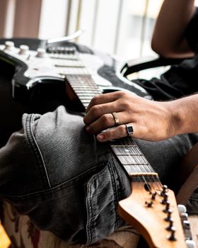 Close-up of a person in jeans holding an electric guitar, capturing a relaxed musician vibe.. pexels, close, person