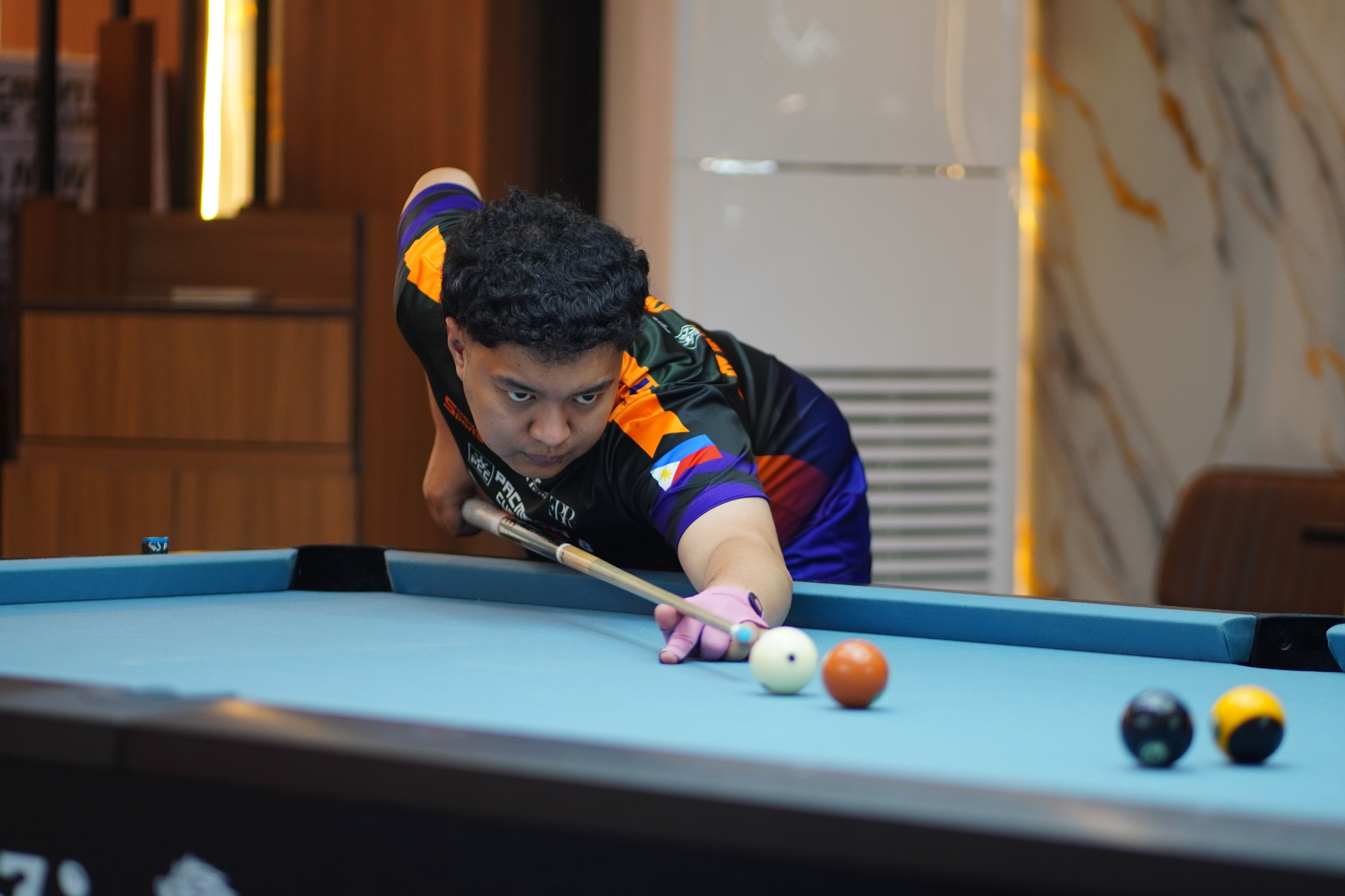 Young billiards player intensely aiming a cue ball indoors. Competitive spirit in action.