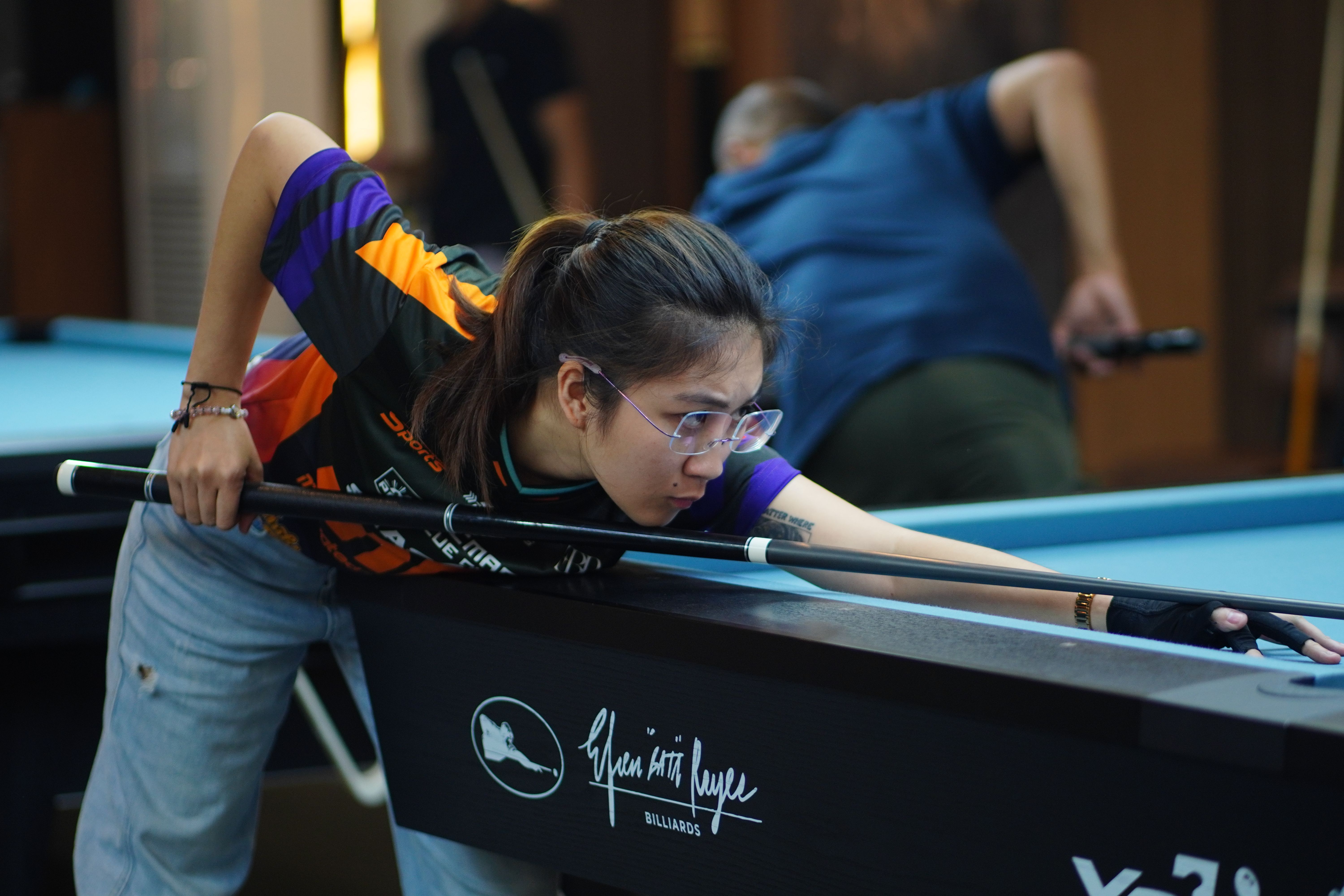 Focused female billiards player aiming shot