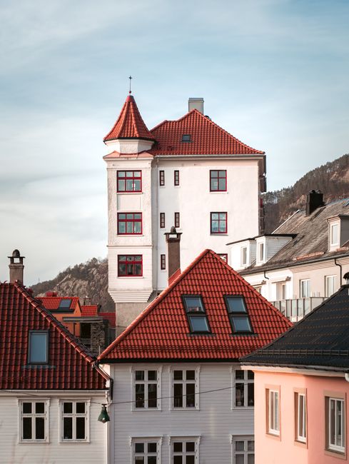Charming European buildings with red roofs against a scenic mountain backdrop.