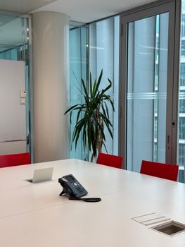 A sleek office conference room in Milan with red chairs and natural lighting from large windows.