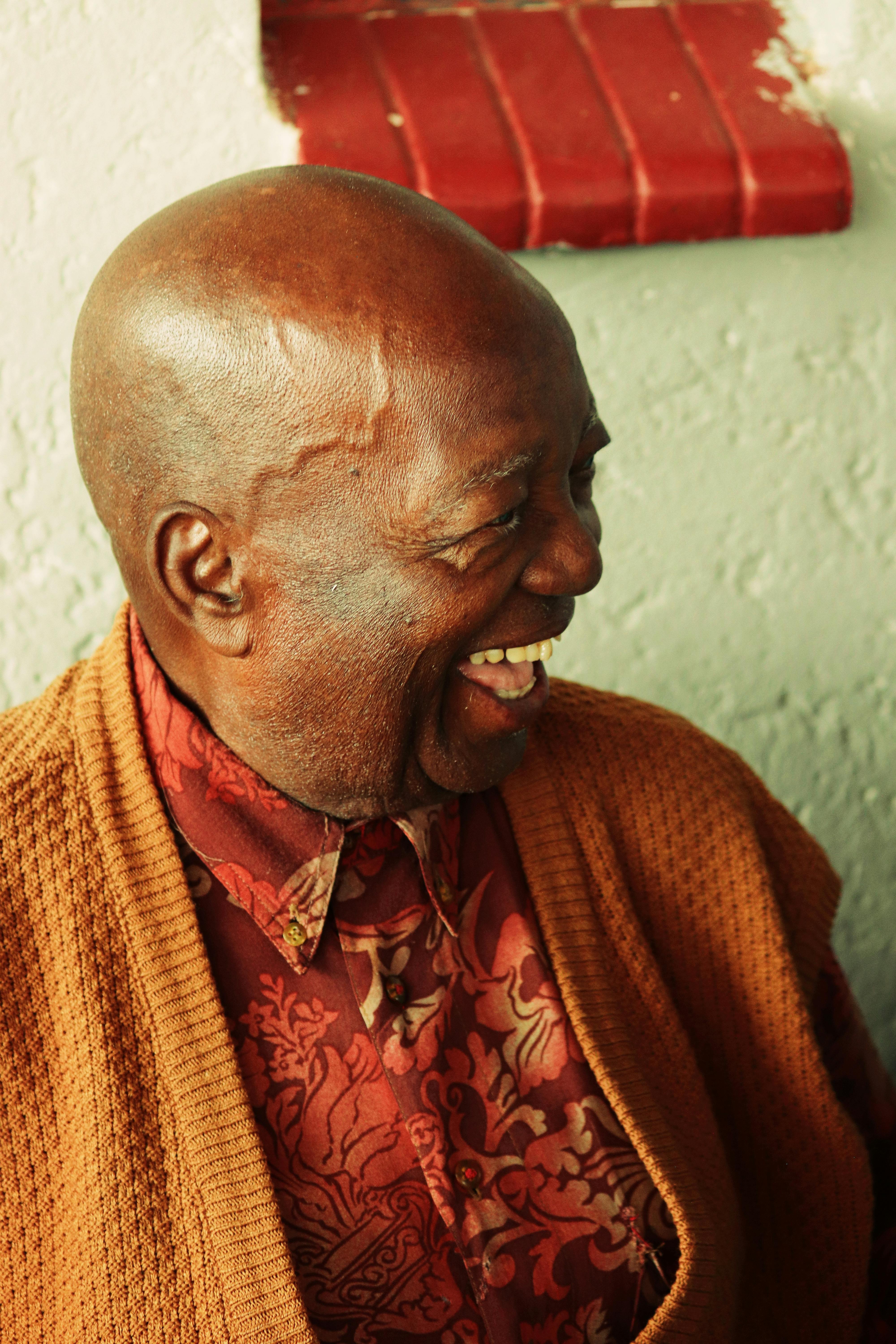Elderly man with a joyful expression laughing indoors. Capturing warmth and happiness.