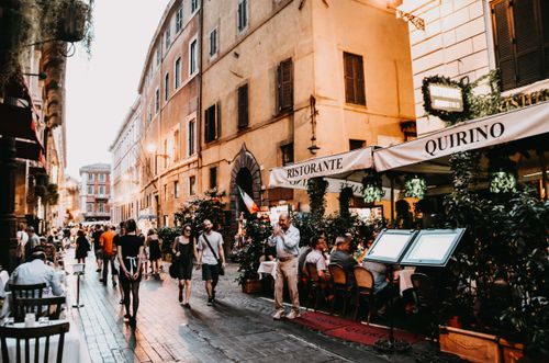 Free Evening view of a lively street in Rome with people dining and strolling. Stock Photo