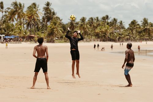 Free A group of friends playing volleyball on a sunny tropical beach, enjoying outdoor sports and fun under palm trees. Stock Photo