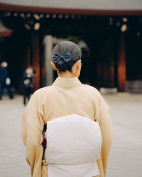 Rear view of a traditional kimono-clad woman in a Japanese temple setting, evoking a sense of cultural elegance.