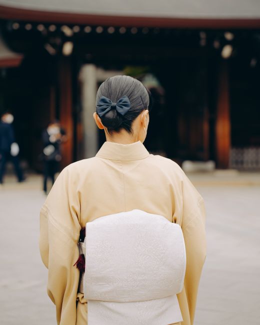 Rear view of a traditional kimono-clad woman in a Japanese temple setting, evoking a sense of cultural elegance.