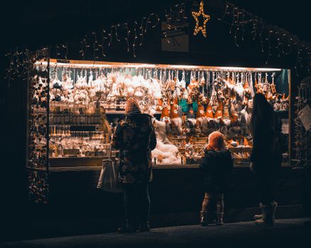 People enjoying a festive winter market stall beautifully lit up at night, perfect for holiday shopping.