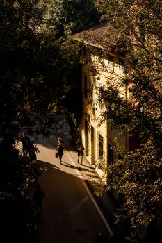 Charming sunset scene in Pisa, Italy, with people strolling down a sunlit street.