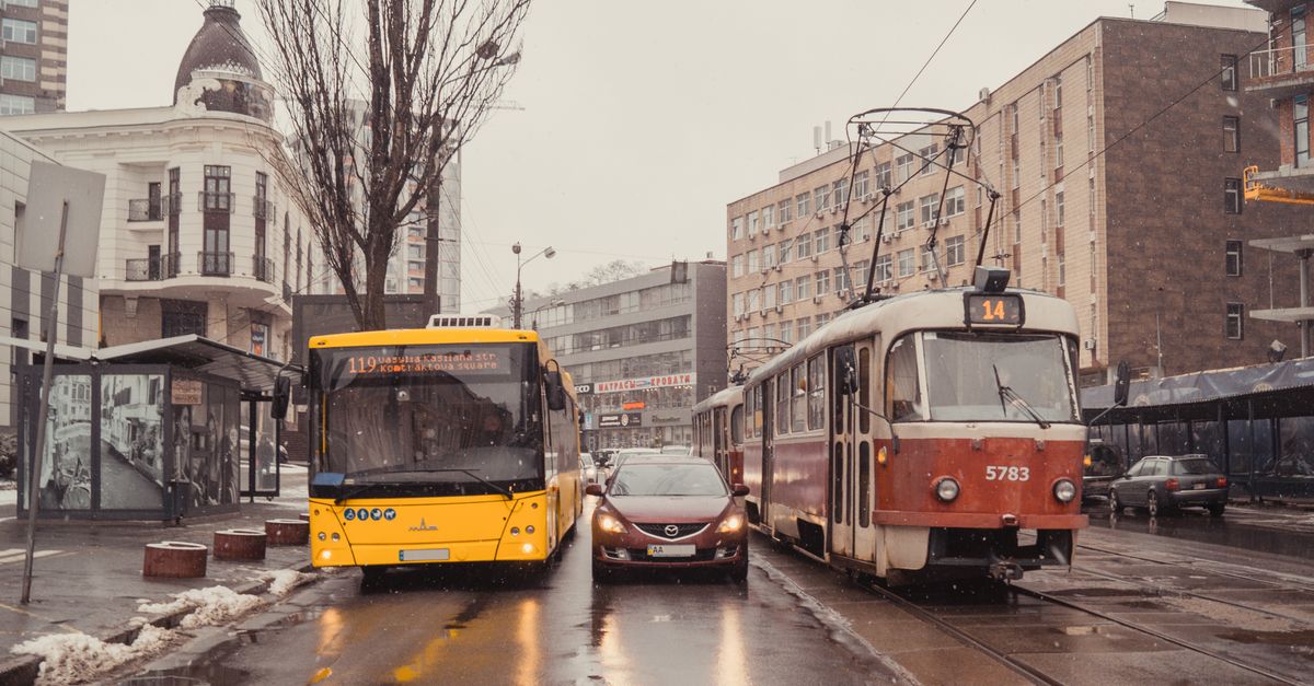 Uma rua da cidade nevada em Kyiv com um bonde, ônibus e carro navegando pelas condições invernais.