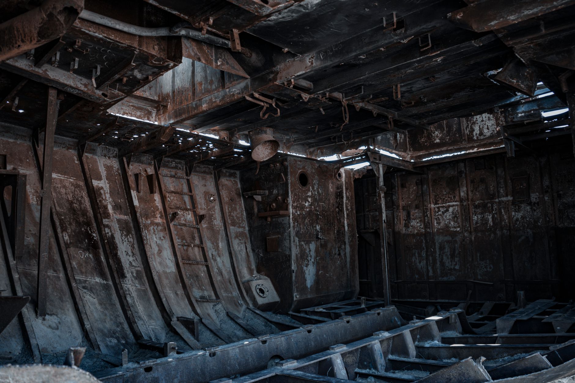 Explore the haunting interior of an abandoned rusty ship in the desert.