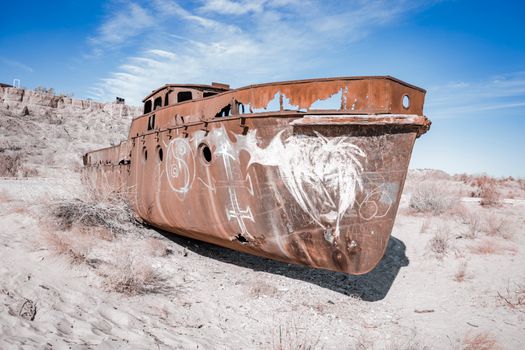 An abandoned rusty ship in the desolate Aral Sea desert, showcasing ecological disaster.