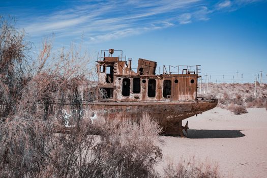 Abandoned rusty ship in the desert of the former Aral Sea, Uzbekistan, showcasing ecological disaster.