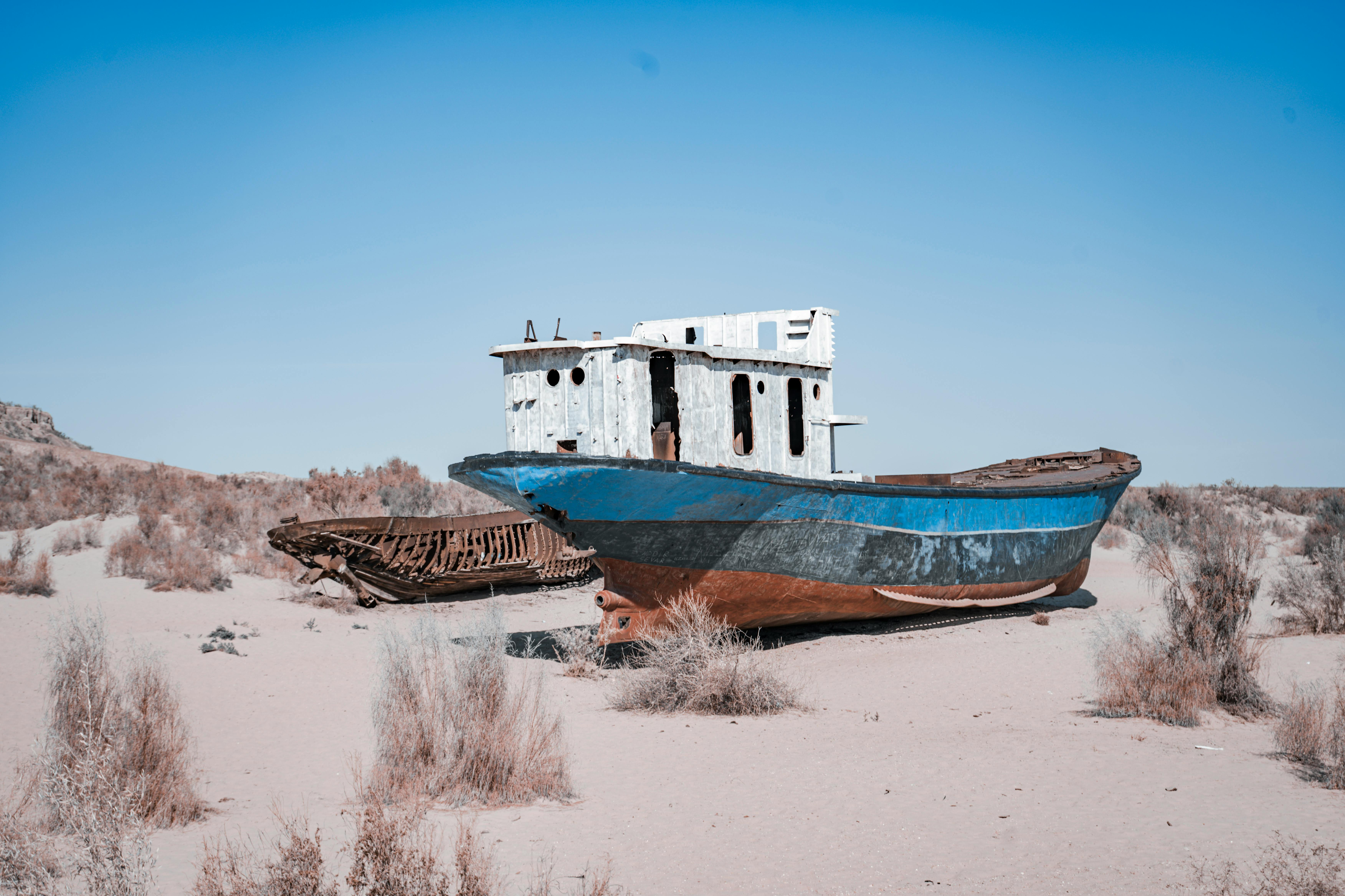 Free Rusty abandoned ships stranded on the Aral Sea desert, highlighting environmental disaster effects. Stock Photo