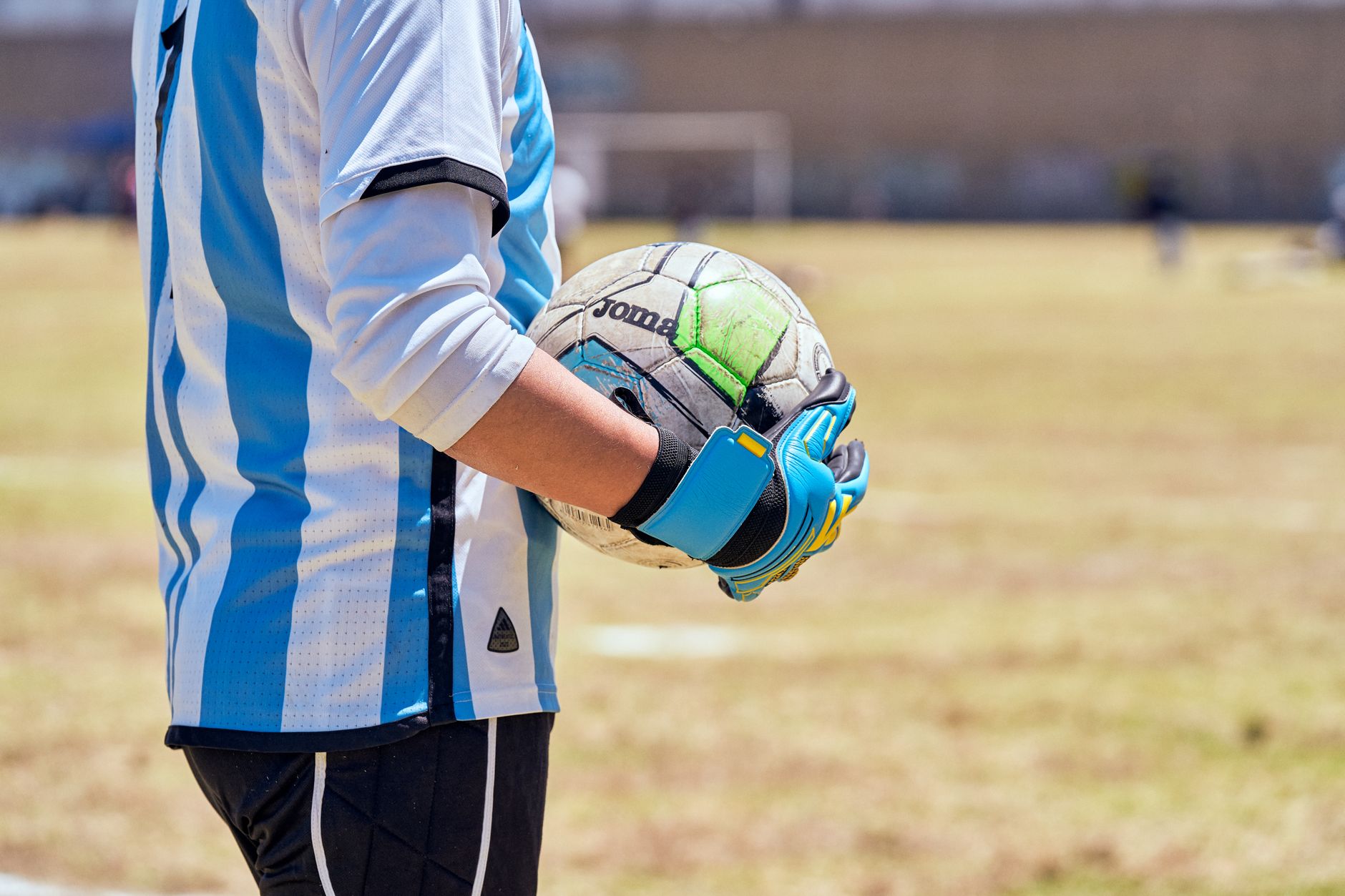 a player holding a smartphone with a football game open beside match notes and a tactical notebook
